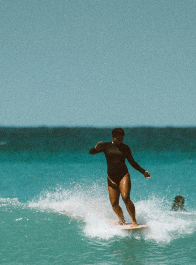 A female surfer mastering a wave with technique, symbolizing the specialized execution and mastery of our specialties in communication and design.